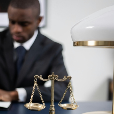 person in background with small scales of justice on desk. Legal billing costings.